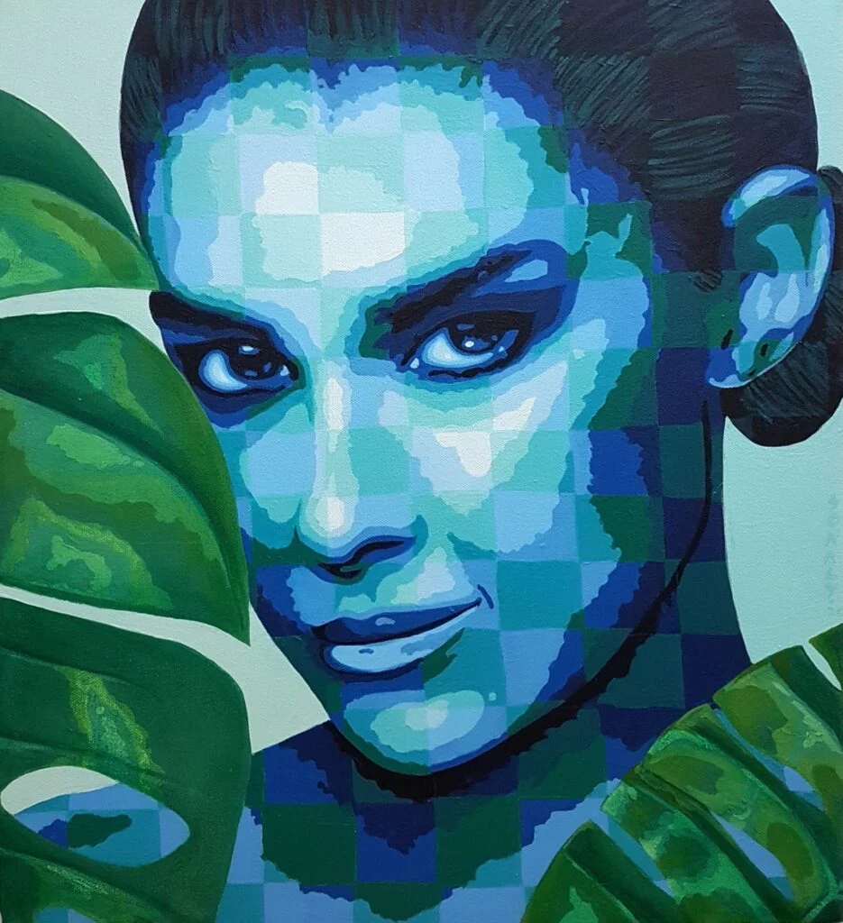 This is an original contemporary portrait painting of a rectangular shape. It is an acrylic on canvas artwork with a light blue-green background. In the center, and occupying the majority of the canvas, is the face of a beautiful young woman with her head at a slight angle. She is looking directly at the viewer with a gentle smile on her face. She is covered in my signature style of checks in subtle, contrasting hues of blue and green. She is surrounded by a beautiful bunch of green leaves. This artwork is from my series "In Harmony with Nature" Through this painting, I aim to capture the awe-inspiring connection between humans and the exquisite tapestry of nature that envelops us. It’s our responsibility to be compassionate towards all living creatures around us and live in harmony with nature. Lady and Leaves, modern portrait artists, art painting online, artwork for home, art for sale online